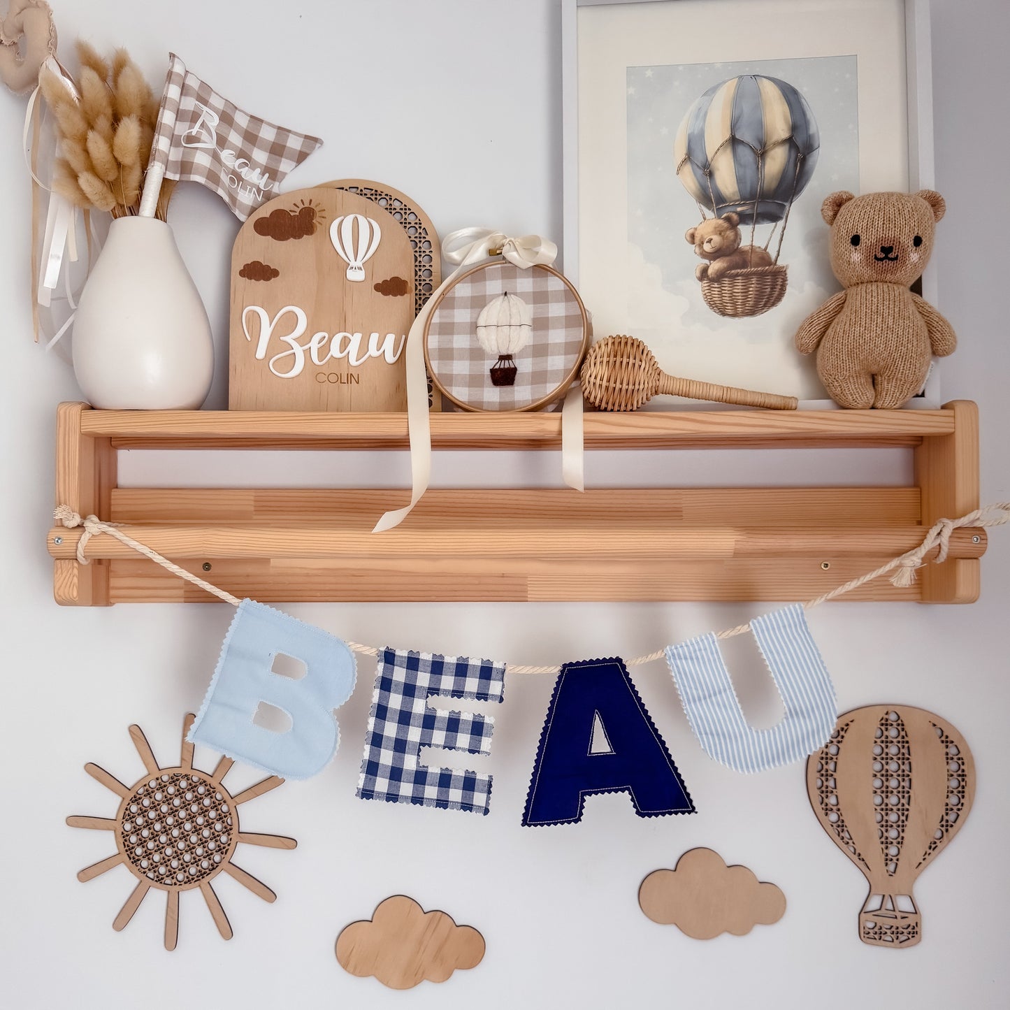 Nursery shelf with decorative items including a teddy bear, wooden letters, and a hot air balloon-themed painting.